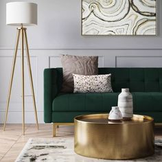 a living room with a green couch and gold coffee table in front of a painting on the wall