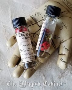 two small bottles sitting next to each other on top of a white cloth covered surface