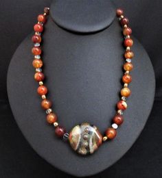 Artisan Statement Necklace~Brown Agate Statement Necklace~Carnelian Southwestern Necklace~Red Carnelian Chunky Necklace~ Handmade Necklace~ This 18" handmade artisan statement necklace features an iridescent artisan SRA focal bead . It is made with 10mm round polished carnelian beads and clear glass disc beads etched in gold.  The colors are a rich rust golden orange with earth tone greens, brown, gold and taupe. Because of its blend of colors, it is difficult to describe it although I think pic Unique Red Agate Beaded Necklaces, Brown Carnelian Gemstone Necklaces, Brown Carnelian Gemstone Necklace, Unique Orange Agate Necklace, Red Carnelian Artisan Jewelry, Artisan Carnelian Orange Jewelry, Artisan Red Carnelian Jewelry, Artisan Orange Carnelian Jewelry, Vintage Agate Beaded Necklaces As Gift