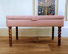 an upholstered bench sits in front of a painting