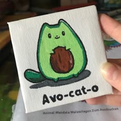 a person holding up a small card with an image of a green cat on it