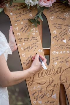 a person writing on a wooden letter with flowers