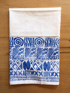 a piece of cloth with blue and white designs on it sitting on a wooden surface