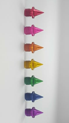 six different colored cones are lined up on a white wall, with one in the middle