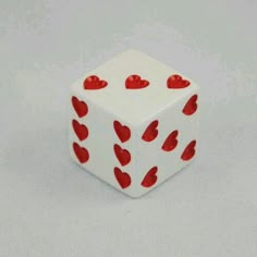 a white dice with red hearts on it