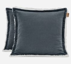 two dark blue pillows with white trims on the sides and one in grey velvet