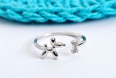 925 Sterling Silver Yarn Tension Ring for Beginning Crocheters & Knitters. This Crochet Ring has a Balloon Animal in the shape of a dog on one side and a bone with sparkly crystals on the other. Use this ring to drape your yarn over, instead of winding the yarn around your fingers for tension.   You can see in the photos the 2 different ways to drape the yarn around the ring for tension.  How to USE:  1. Make your slip stitch and set the yarn down. 2. Adjust the ring to fit your index finger (slightly loose) on the hand that you use to hold your yarn.  If you crochet with your right hand, put the ring on your left hand and vice versa.  If you are knitting, put the ring on the hand that normally holds the yarn.   3. Slide the ring to just below the knuckle.   4. Follow the photos for 2 ways Knitting & Crochet Tools, Tension Ring, Crochet Rings, Ring Tutorial, Knitting Supplies, Balloon Animals, Slip Stitch, Stitch Markers, 925 Sterling Silver Ring