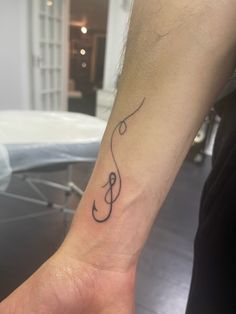 a small tattoo on the wrist of a person with a treble in black ink