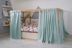 a child's bed with curtains on the sides and a stuffed animal in the middle