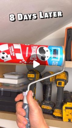 a person holding a paint roller in front of a shelf filled with tools and construction equipment