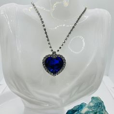 Experience the magic and elegance of the Titanic with our stunning Titanic Medallion Amulet. The bright blue pendant, decorated with sparkling rhinestones, attracts everyone's attention and gives every outfit a touch of glamor and romance. The high-quality silver-plated chain with a length of approx. The height is approx. 55 cm, which can be extended by a further 5 cm, perfectly complements the enchanting medallion. This unique piece of jewelry, reminiscent of the famous Titanic diamonds, will s Party Crystal Rhinestone Heart Pendant Necklace, Royal Blue Crystal Jewelry For Party, Party Jewelry With Sapphire And Sparkling Stones, Blue Heart Pendant Jewelry For Party, Jeweled Crystal Rhinestone Pendant Necklace, Jeweled Pendant Rhinestone Necklace, Crystal Rhinestone Jeweled Pendant Necklace, Glamorous Jeweled Rhinestone Necklace As Gift, Jeweled Crystal Rhinestone Necklace As Gift