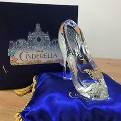 a clear shoe sitting on top of a blue satin covered bag next to a box