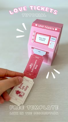 a pink ticket dispenser being held by someone's hand with love tickets on it