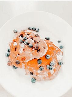 a white plate topped with blueberries and pancakes