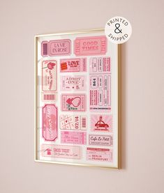 a pink and gold framed wall hanging with some stickers on it's side