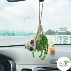 two stuffed animals hanging from a rope in the dashboard of a car on a road