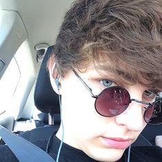 a young man wearing headphones in the back seat of a car with sunglasses on