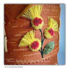 the flowers are made out of yellow and red yarn on top of a tree trunk