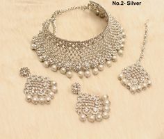 * SIlver choker necklace Set with earrings Tikka as shown in the pic. * Studded with crystals and rhinestones. * One of a Kind. *No.1- Silver *Necklace Width- 1.6 inches(included drops) * Earrings Length: 2.3 inches(included drops) *Earrings Breadth- 1.6 inches *No.2- silver *Necklace Width- 2 inches(included drops) * Earrings Length: 2.6 inches(included drops) *Earrings width- 1.4 inches White Metal Choker For Wedding, White Metal Wedding Choker, Silver Round Choker For Party, Traditional Silver Choker For Formal Occasions, Traditional Silver Formal Choker, Silver Party Choker, Silver Choker For Celebrations, Silver Metal Jewelry Sets For Celebration, Silver Festive Choker Jewelry