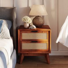 a nightstand with a lamp and flowers on it