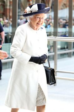 the queen of england is wearing a white coat and matching hat with her black purse