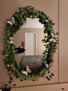 a person taking a photo in front of a mirror with flowers and leaves on it