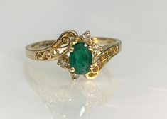 Dainty Emerald Ring, Emerald Ring Vintage, Filigree Gold Ring, Emerald Bypass Ring, Oval Emerald Ring, Dainty Gold Ring, Vintage Bypass Ring A delicate and delightful vintage bypass ring featuring an oval shaped emerald center stone weighing 0.46 carats accented by 0.05 carats of white diamonds set in solid 14k gold with unique filigree detailing. *Ring size: US 7 1/2 *Complimentary resizing is available up to 3 sizes larger or smaller than stated size. *Ring weight: 2.26 grams Stone dimensions: Fine Jewelry Ring With Intricate Oval Design, Oval Ring With Intricate Design In Fine Jewelry, Oval Fine Jewelry Ring With Intricate Design, Antique Gold Emerald Ring With Intricate Design, Signate Ring, Vintage Green Emerald Open Ring, Vintage Engagement Rings Unique 1920s Emerald, Oval Emerald Ring With Intricate Design, Vintage Handmade Green Emerald Ring