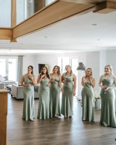 a group of women standing next to each other in front of a living room filled with furniture