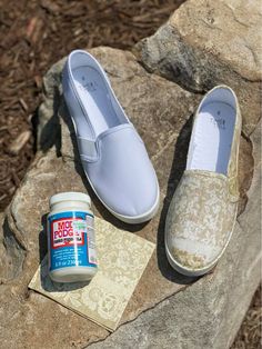 a pair of shoes sitting on top of a rock next to a jar of glue