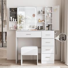 a white dressing table with a mirror and stool in front of it, next to a window