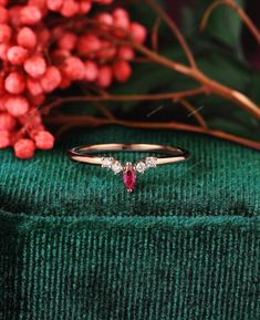 a close up of a ring on top of a green cloth with flowers in the background