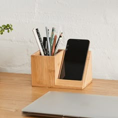 a wooden desk with a laptop and pen holder