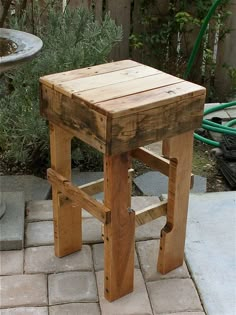 a wooden stool sitting on top of a brick patio