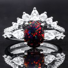 a black opal and white diamond ring set on a reflective surface with the words never above it