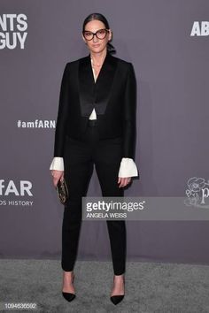 an older woman in black and white outfit poses on the red carpet at amfar awards