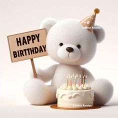 a white teddy bear holding a sign that says happy birthday with candles on top of it