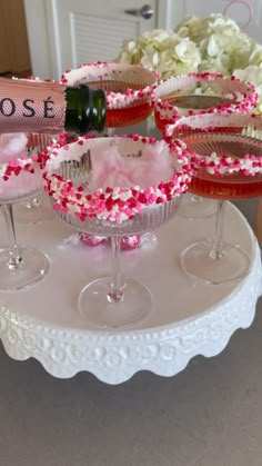 three wine glasses filled with pink and white confetti sit on a cake stand