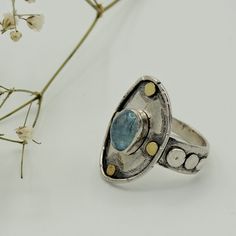 "A beautiful and very interesting Aquamarine, silver and gold ring. Minimalistic elegance is the main attribute of this beautiful piece. The design recalls ancient times and cultures, and some pieces of its surface are oxidated and scratched to give a more textured feeling to it. The main protagonist, is a transparent, clear and intense Aquamarine. The main material of this beauty is the sterling silver, while the details around the gem are made of 18 kt gold. This piece is entirely made by myse Handmade Adjustable Sapphire Open Ring, Handmade Topaz Open Ring Gift, Handmade Adjustable Topaz Ring For Anniversary, Handmade Open Topaz Ring In Sterling Silver, Unique Handmade Moonstone Promise Ring, Handmade Adjustable Open Sapphire Ring, Handmade Open Topaz Ring For Gift, Handmade Open Topaz Ring Gift, Handmade Silver Topaz Open Ring