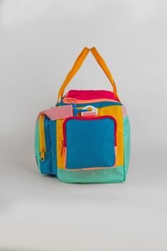 a multicolored handbag is sitting on a white surface and it has two handles