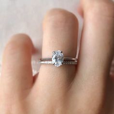 a woman's hand holding a ring with a diamond on the middle of it