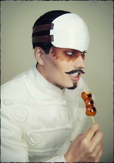 a man with a mustache and moustache on his face is holding a skewer of food