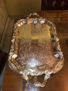 an ornate silver tray sitting on top of a wooden table