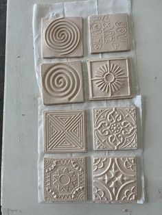 several different types of ceramic tiles on a white surface with one being cut out and the other is made from clay