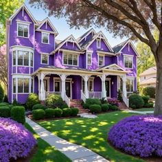 a purple house with white trim and lots of flowers on the front lawn in front of it