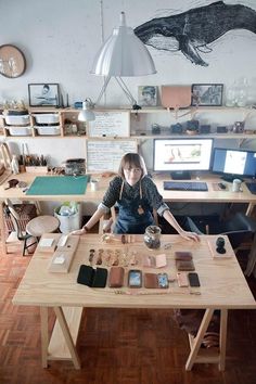 a woman sitting at a desk with many items on it