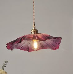 a pink flower hanging from a light fixture in a room with flowers on the table