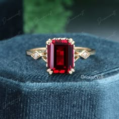 a red stone ring sitting on top of a blue velvet cushion