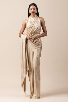 Gold pre-stitched lam  jersey metallic wrap saree. Comes with draped halter blouse.
Component: 2
Neckline: Halter
Sleeve Length: Sleeveless
Fabric: Lam  Jersey
Color: Gold
Pre-draped saree
Draped blouse
Cutout back
Closure: Blouse: Back hooks - Aza Fashions Drape Sarees, Halter Neck Blouses, Saree Wearing, Saree Wearing Styles, Draped Saree, Saree Draping Styles, Modern Saree, Draping Fashion, Saree Gown