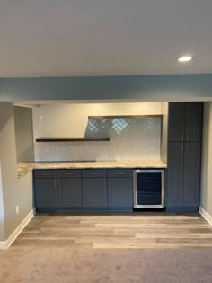 an empty kitchen with blue cabinets and marble counter tops in a home remodeling project