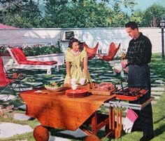 a man and woman standing next to a table with food on it